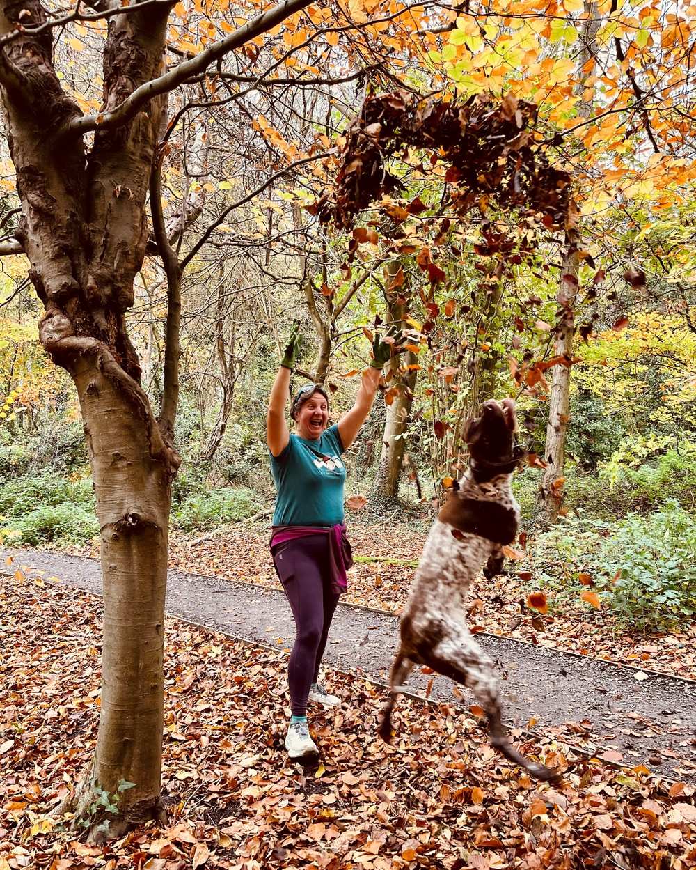 Woman and her dog playing in leaves
