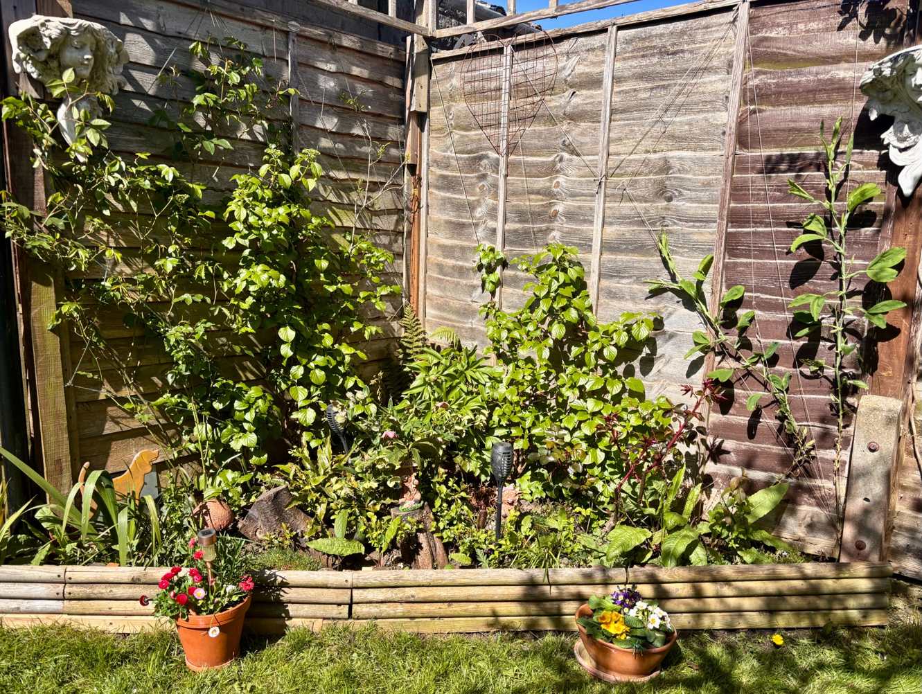 Sunny garden corner with colourful flowers and ornaments
